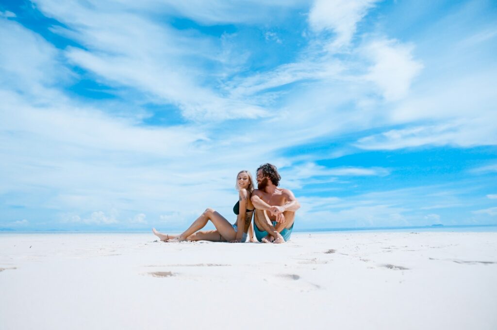 man and woman sitting on beach